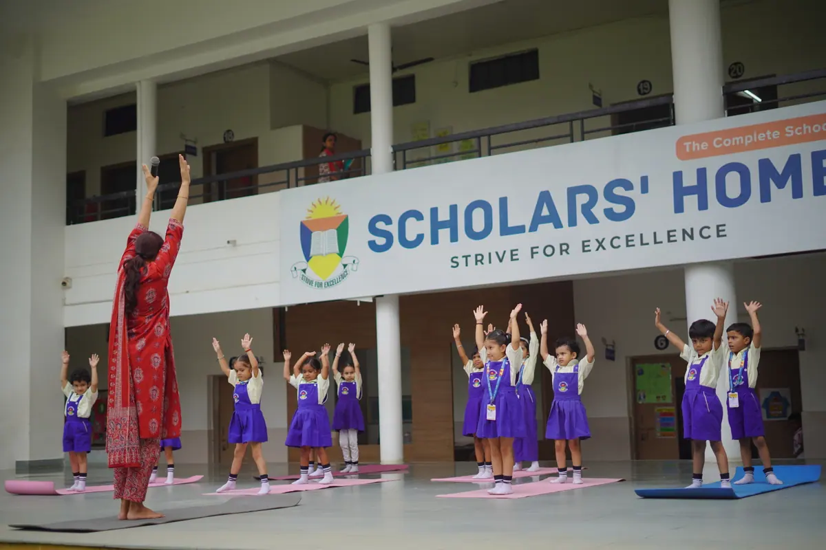 Pre-Primary children doing morning yoga with their teacher in the school atrium at Scholars' Home, Gomti Nagar
